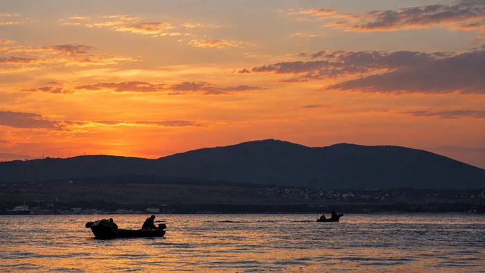 Геленджикская бухта на закате, море, лодки и Маркотхский хребет.